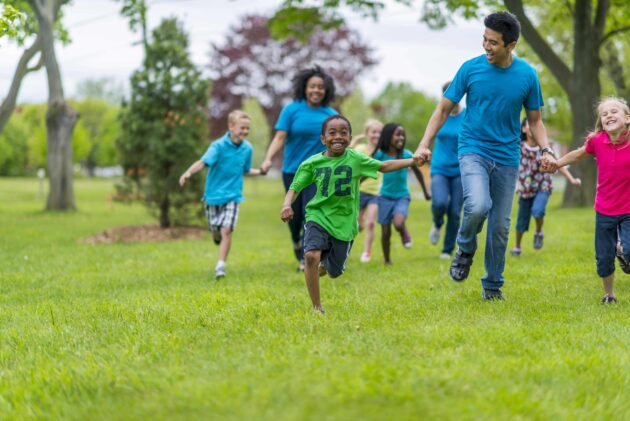 Adults and kids holding hands and racing.